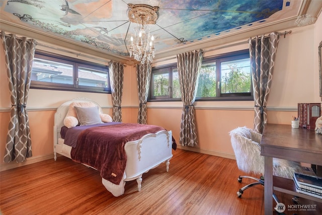 bedroom featuring baseboards, wood finished floors, and a notable chandelier