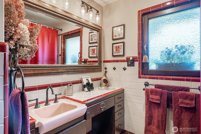 full bath with vanity, curtained shower, a wealth of natural light, and tile walls