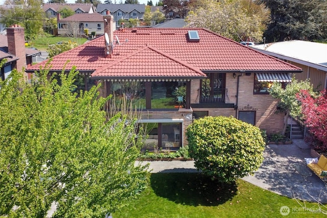 rear view of house with brick siding, a tiled roof, and a residential view
