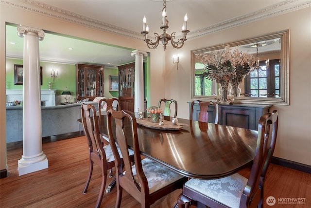 dining space featuring ornamental molding, decorative columns, wood finished floors, and a chandelier