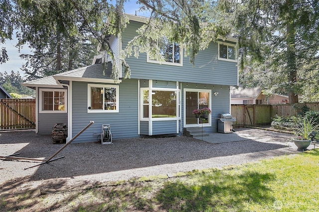 rear view of property with entry steps, a patio, and a fenced backyard