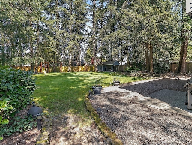 view of yard featuring a fenced backyard, a patio, and an outdoor structure