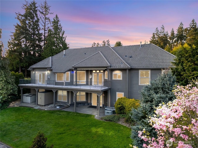 10910 48th Street Ct E, Edgewood, WA 98372 - back of house at dusk featuring a patio, a yard, a tiled roof, and a wooden deck