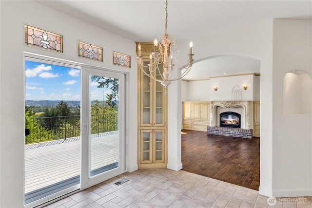 10910 48th Street Ct E, Edgewood, WA 98372 - unfurnished dining area with arched walkways, a glass covered fireplace, stone finish floors, and a chandelier
