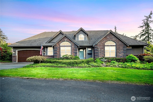 10910 48th Street Ct E, Edgewood, WA 98372 - traditional-style house with brick siding, a tile roof, a yard, driveway, and a garage