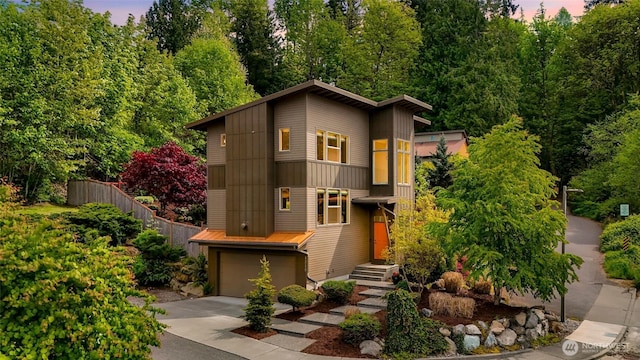 view of front of property with fence, concrete driveway, a garage, a standing seam roof, and metal roof