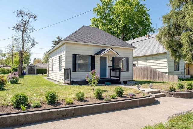 616 Pleasant St, Walla Walla, WA 99362 - view of front of property featuring an outdoor structure, a front lawn, fence, roof with shingles, and a storage shed