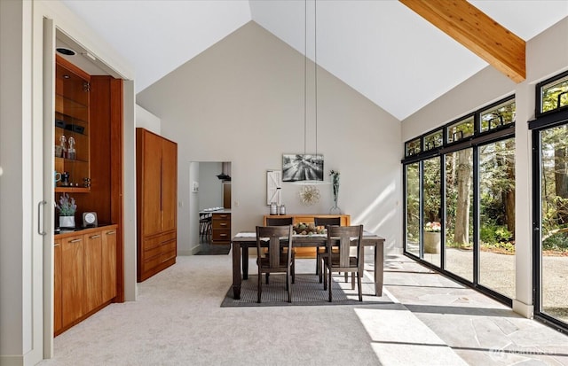 dining area featuring high vaulted ceiling and light carpet