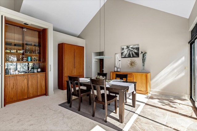 dining room featuring high vaulted ceiling and light carpet