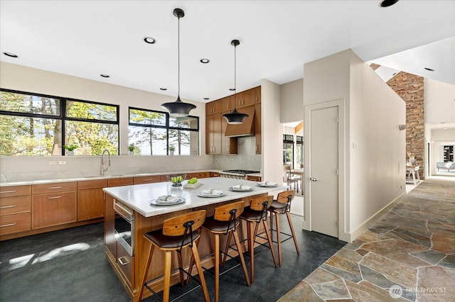 kitchen with tasteful backsplash, brown cabinets, a sink, light countertops, and stainless steel appliances