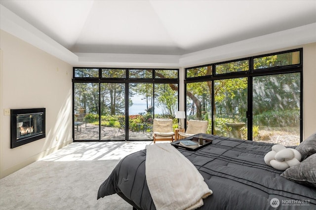 carpeted bedroom with a glass covered fireplace, access to outside, and lofted ceiling
