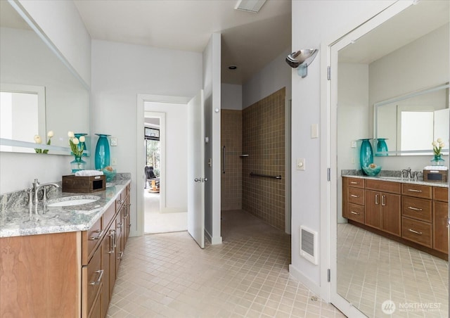full bath with walk in shower, two vanities, a sink, and visible vents