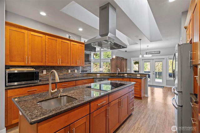 kitchen with a sink, stainless steel appliances, a peninsula, and island exhaust hood