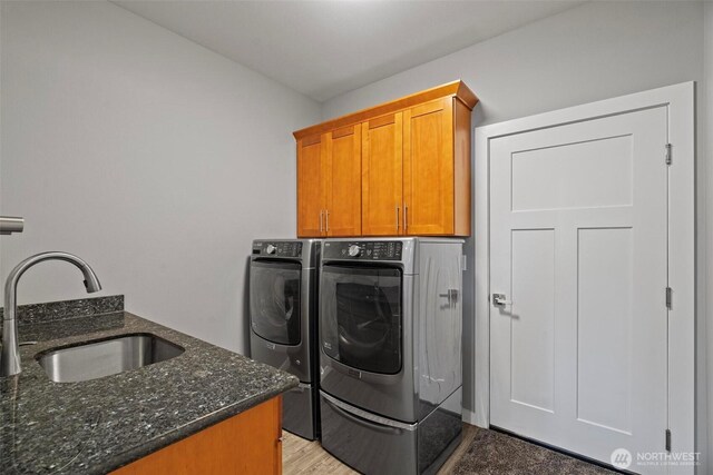 laundry room with a sink, cabinet space, and washer and clothes dryer