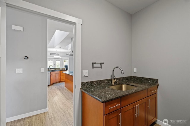 bar with a sink, baseboards, light wood-style floors, and dishwasher