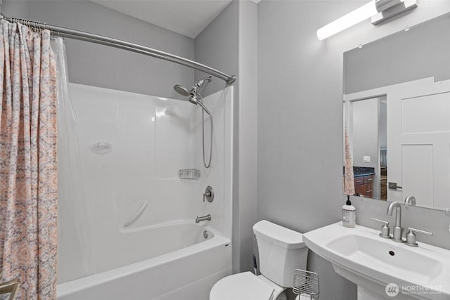 bathroom featuring a sink, shower / bath combo with shower curtain, and toilet