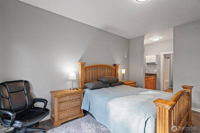 bedroom featuring baseboards, ensuite bath, and wood finished floors