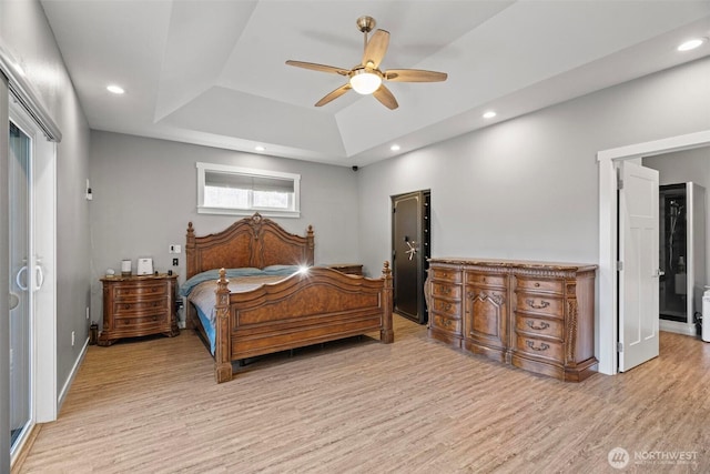 bedroom with recessed lighting, light wood finished floors, ceiling fan, and a tray ceiling