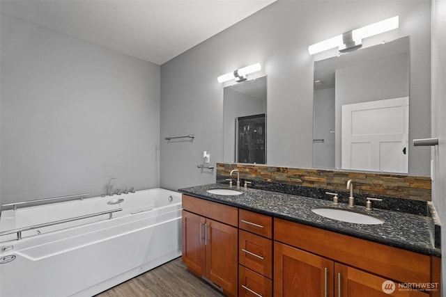 full bathroom with double vanity, a sink, a garden tub, and wood finished floors