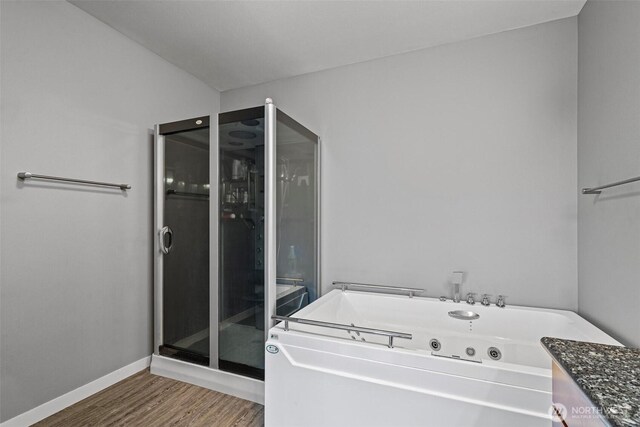 full bathroom featuring baseboards, wood finished floors, and a jetted tub