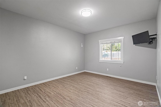 unfurnished room featuring baseboards, wood finished floors, and visible vents