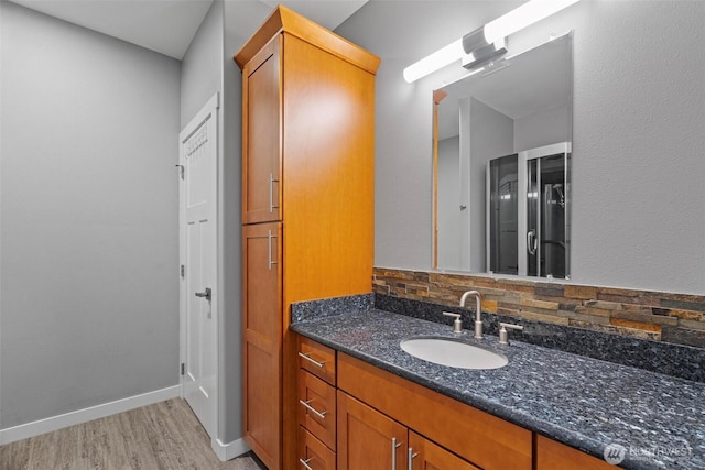 bathroom with baseboards, tasteful backsplash, wood finished floors, and vanity
