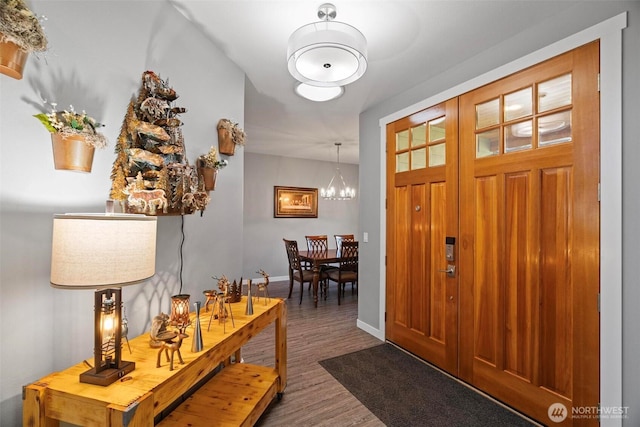 entryway featuring baseboards, an inviting chandelier, and wood finished floors