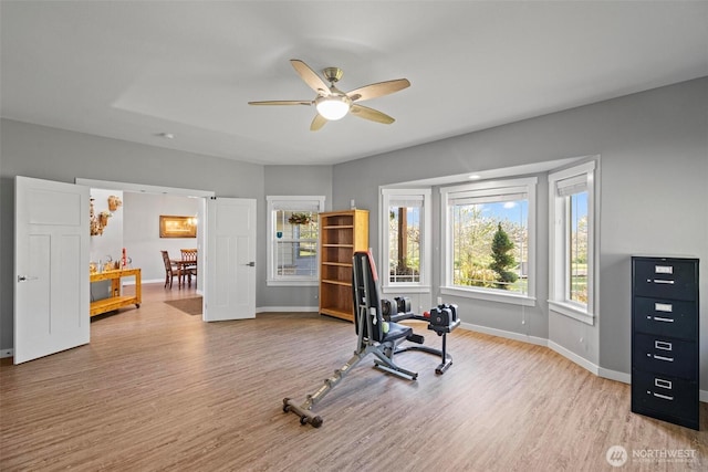 exercise area featuring a ceiling fan, baseboards, and wood finished floors