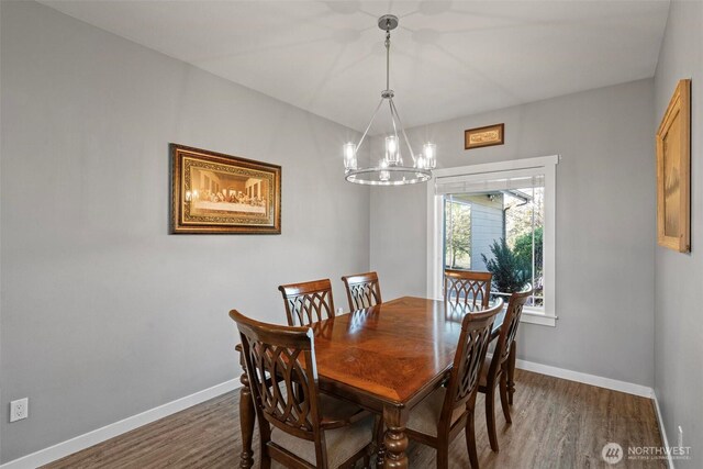 dining area featuring an inviting chandelier, baseboards, and dark wood-style flooring