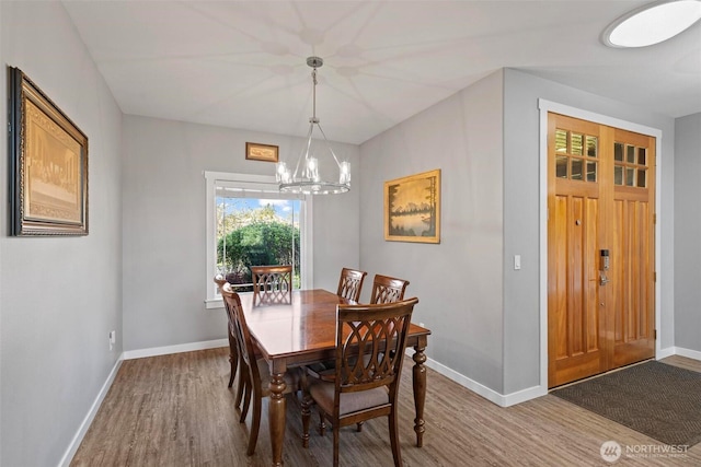 dining area featuring baseboards, wood finished floors, and a notable chandelier