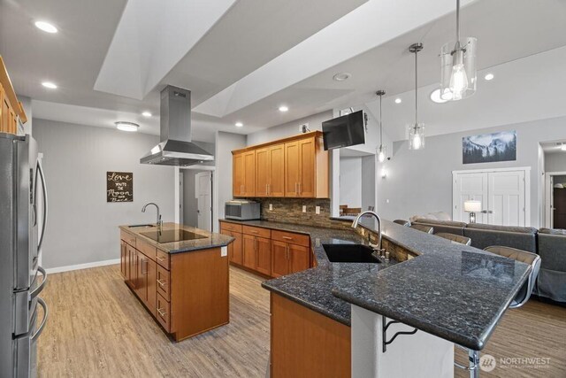 kitchen with a sink, a breakfast bar, stainless steel appliances, and island exhaust hood