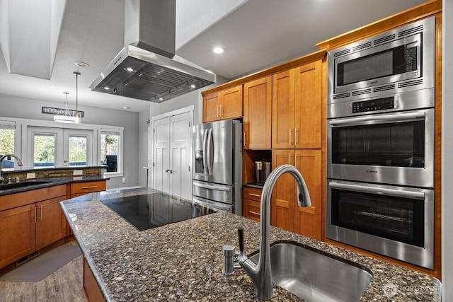 kitchen with brown cabinets, a sink, appliances with stainless steel finishes, and island range hood