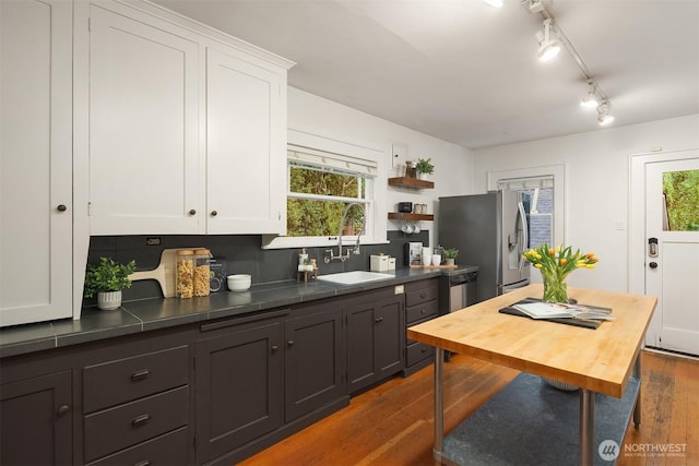 kitchen with stainless steel appliances, dark wood-style floors, white cabinetry, and a sink