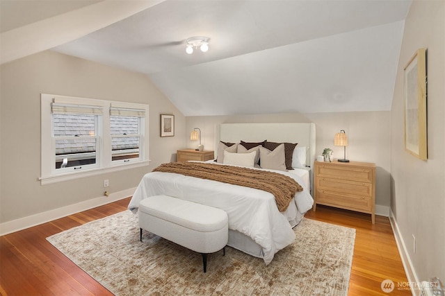 bedroom with baseboards, vaulted ceiling, and wood finished floors
