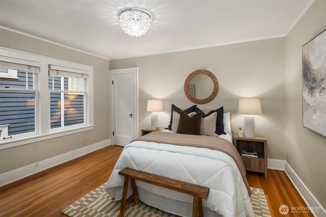 bedroom featuring crown molding, baseboards, and wood finished floors
