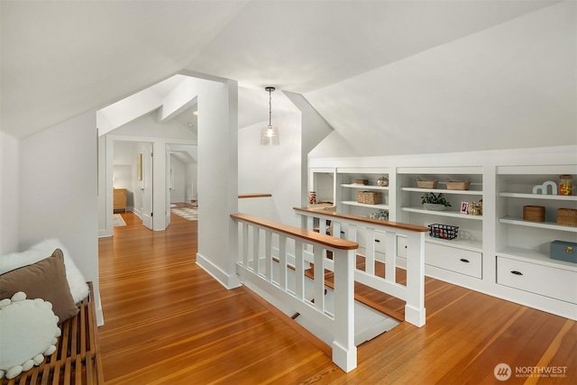 hall featuring lofted ceiling, wood finished floors, and an upstairs landing