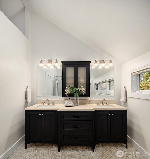 bathroom featuring double vanity, baseboards, and a sink
