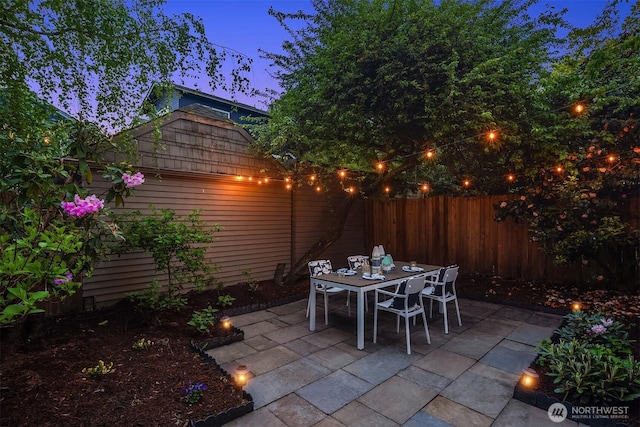 patio terrace at dusk featuring a fenced backyard and outdoor dining space