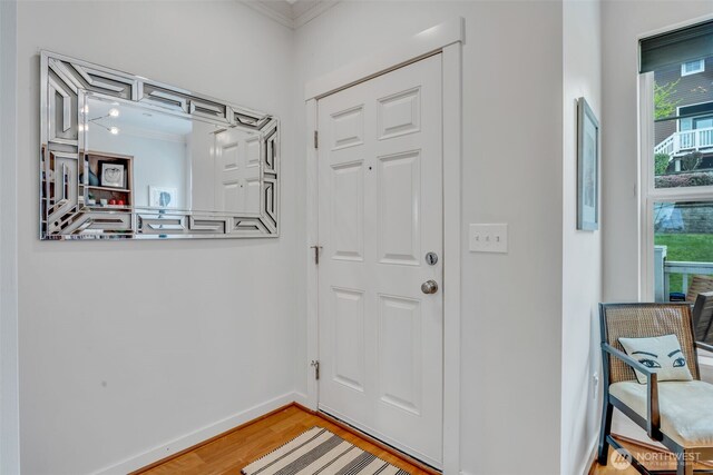 entrance foyer with crown molding, baseboards, wood finished floors, and a wealth of natural light