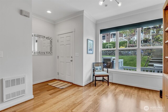 entryway with crown molding, light wood-style floors, and baseboards