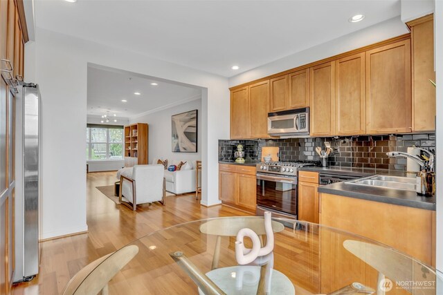 kitchen with dark countertops, light wood-style floors, recessed lighting, backsplash, and stainless steel appliances
