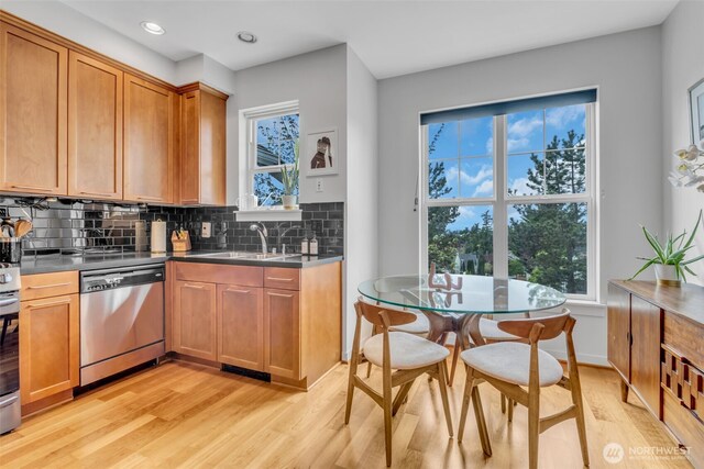 kitchen featuring dishwasher, brown cabinets, a sink, light wood finished floors, and backsplash