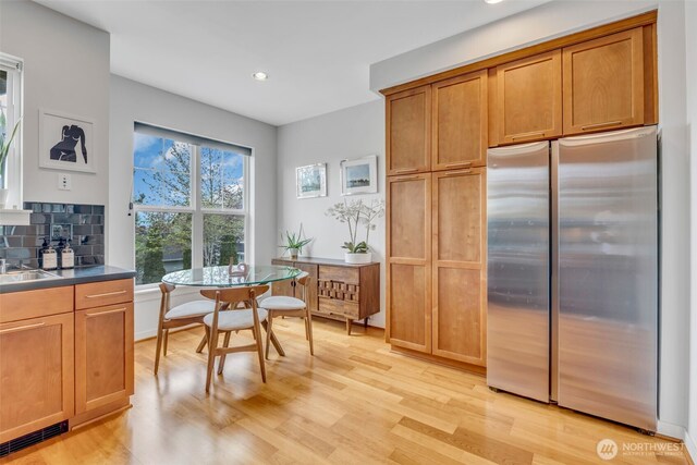 kitchen featuring recessed lighting, tasteful backsplash, freestanding refrigerator, and light wood-type flooring