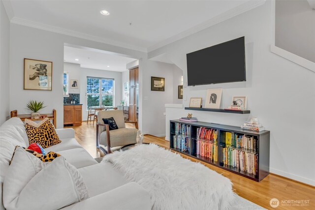 living room with recessed lighting, ornamental molding, light wood finished floors, and baseboards