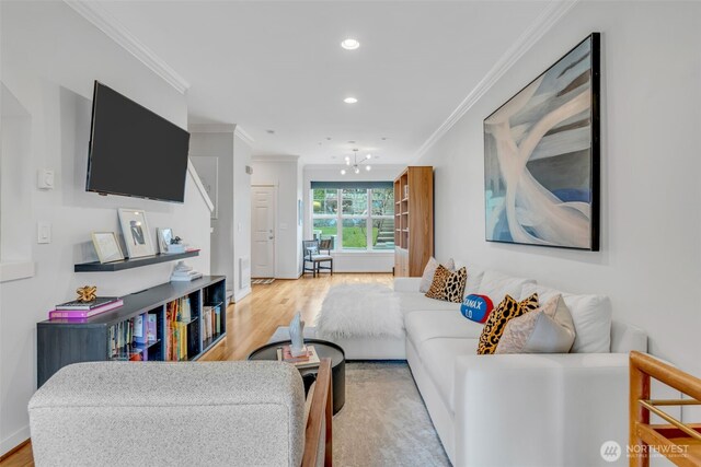 living room featuring recessed lighting, a notable chandelier, ornamental molding, and light wood-style floors