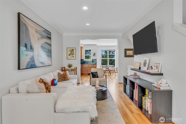living area with crown molding, recessed lighting, and light wood-style floors