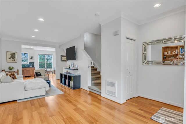 living area featuring crown molding, visible vents, and stairway
