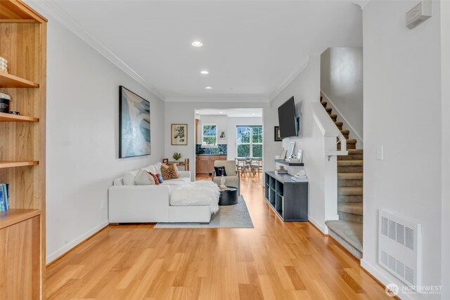 living room featuring ornamental molding, heating unit, light wood-style floors, stairway, and recessed lighting
