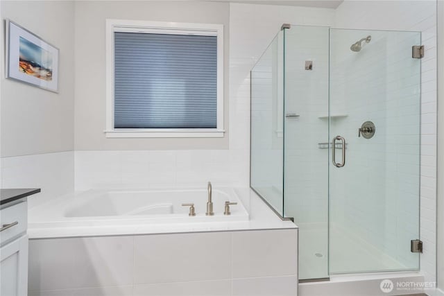 bathroom with a shower stall, a bath, and vanity