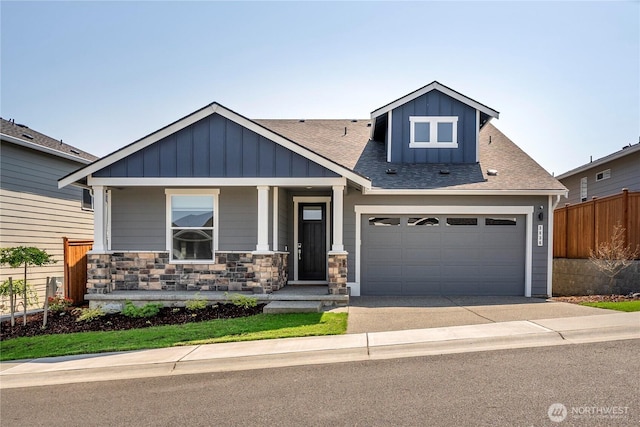 craftsman-style house featuring fence, roof with shingles, board and batten siding, a porch, and concrete driveway